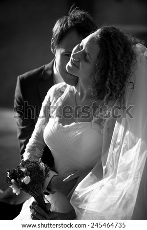 Black and white romantic portrait of groom kissing smiling bride in cheek