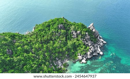 Verdant forests cascade down to meet distinctive rock formations, where the azure sea gently kisses the shore in a breathtaking spectacle. Drone aerial view. Koh Tao, Thailand. 

