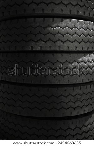 Close up detail photo visual view of a textured striped pile of black dark tires in a storage of a garage for automobile car drive wheel darness full screen absctract texture background