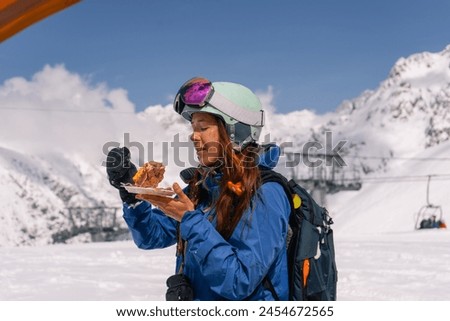 Woman skier snowboarder having lunch outdoors while skiing at ski resort in high mountains