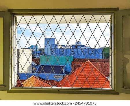 The picture shows a window with iron bars in the morning with sunny weather.