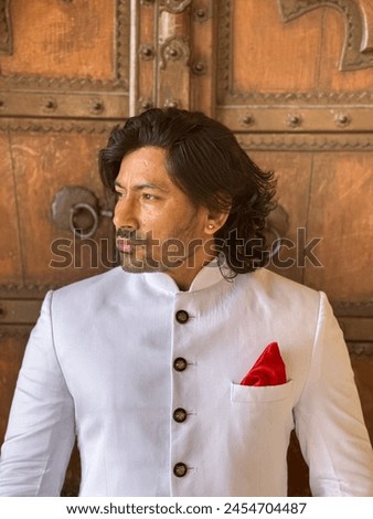 graceful man showcases cultural elegance in traditional attire, exuding confidence and heritage in a single pose Royalty-Free Stock Photo #2454704487