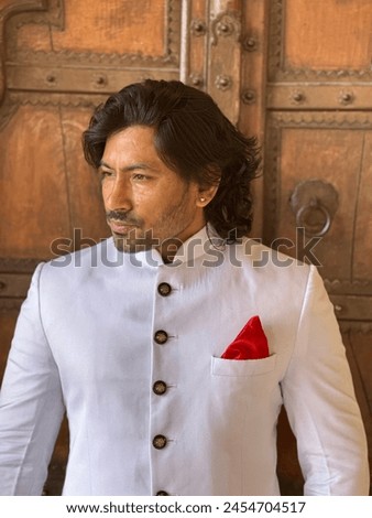 graceful man showcases cultural elegance in traditional attire, exuding confidence and heritage in a single pose Royalty-Free Stock Photo #2454704517