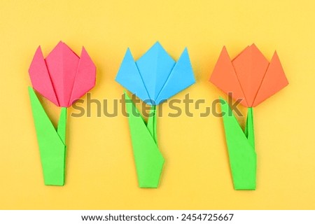 Bright origami tulip flowers on a yellow background.