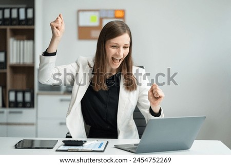Overjoyed charming excited caucasian woman business woman worker using smartphone and laptop working in office, feeling happy. Royalty-Free Stock Photo #2454752269