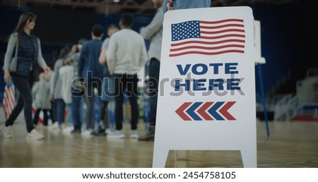 Vote here sign on the floor. Queue of multi ethnic American citizens come to vote in polling station. National Election Day in United States. Political races of US presidential candidates. Civic duty.