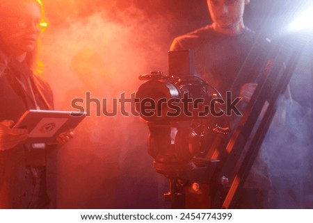 Background image of pro video camera equipment backstage in red neon light, copy space