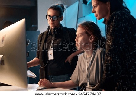 Side view portrait of three female creators looking at computer screen together in studio copy space