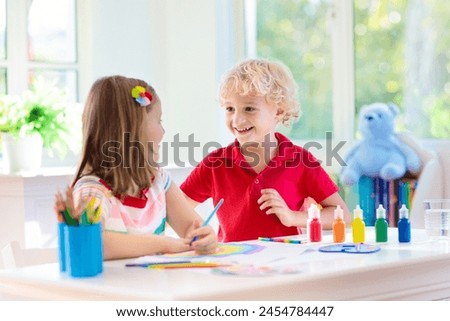 Kids paint. Child painting in white sunny study room. Little boy and girl drawing rainbow. School kid doing art homework. Arts and crafts for kids. Paint on children hands. Creative little artist at w