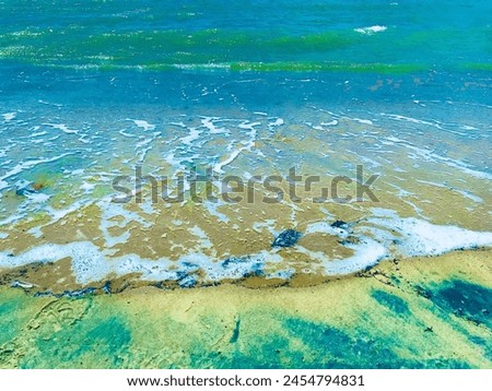 Picture a calm beach with clear blue water and golden sand. The sun shines, waves gently roll in, creating a peaceful scene. It's a perfect spot for a relaxing vacation