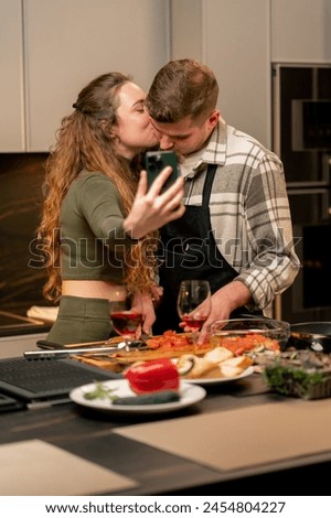young couple in love in beautiful kitchen preparing dinner together and taking pictures