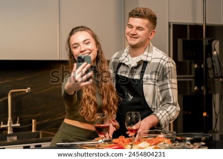 young couple in love in beautiful kitchen preparing dinner together and taking pictures