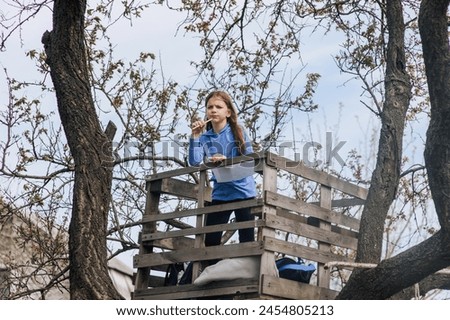 Beautiful pensive girl, inspired dreamy child teenager 8 years old stands on a wooden bridge outdoors in nature, writing poetry and drawing a picture of a landscape. Photography, portrait. Royalty-Free Stock Photo #2454805213