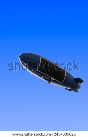 dirigible airship zeppelin over clean blue sky background Royalty-Free Stock Photo #2454805825