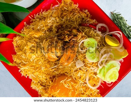 Savory chicken biryani artfully arranged in a vibrant red dish, invitingly presented on a table. Aromatic spices and fluffy basmati rice are perfectly cooked and served.