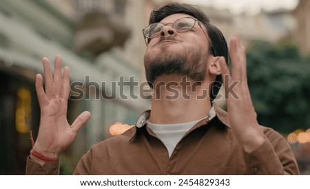 Annoyed angry mad stressed Indian Arabian ethnic male student man guy businessman client customer furious business fail loss dissatisfaction frustration headache touch holding head outside city street Royalty-Free Stock Photo #2454829343