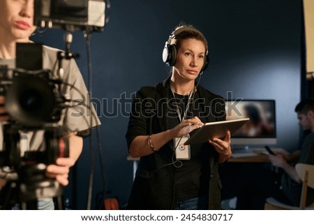 Waist up portrait of adult woman as production assistant working on set and wearing headset copy space