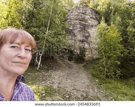 Happy female blonde tourist taking selfie picture with smart mobile phone outside. Middle aged woman having fun on adventure trip in mountain