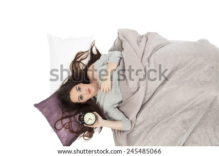 Beautiful woman in bed while holding an alarm clock