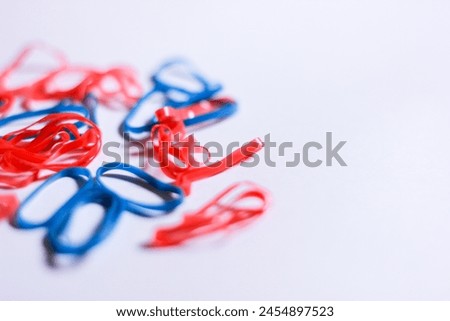bokeh close up shot of vibrant red and blue small rubber band isolated on white background with large copy space for content