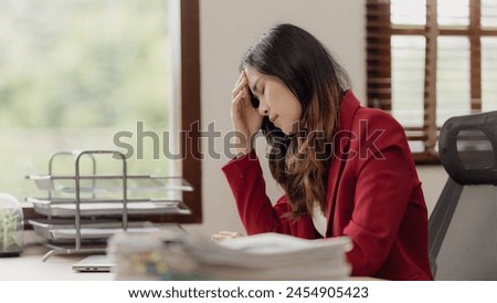 Asian woman using laptop computer and working at office with calculator document on table, planning to analyze financial report, business plan, financial investment