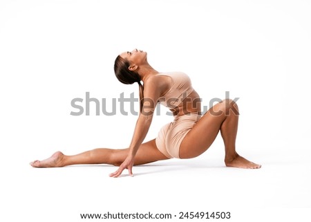 Young woman gymnast stretching on white background