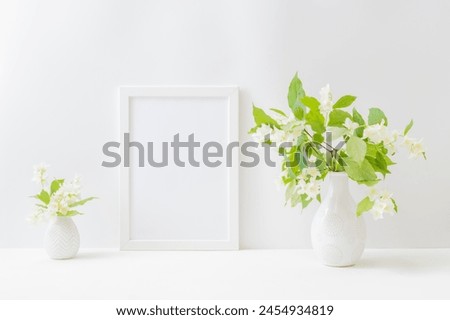 Home interior with decor elements. Mockup with a white frame and white spring flowers in a vase on a light background