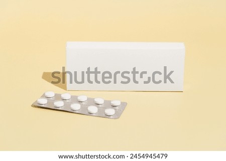 White mockup box and blister with pills of antidepressants, dietary supplements, vitamin D or oral contraceptives on yellow isolated background. Image for your design Royalty-Free Stock Photo #2454945479