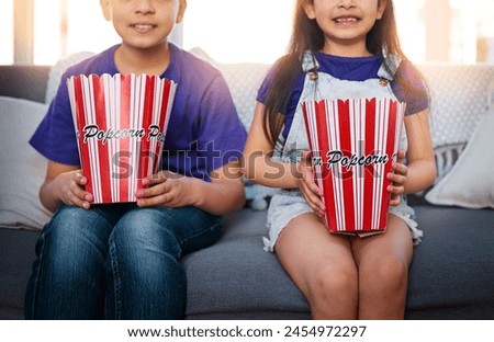 Kids, popcorn and sofa to watch, cartoon and movie with food, growth and development of siblings. Children, boy and girl in living room, couch and eating for film, house and waiting for start