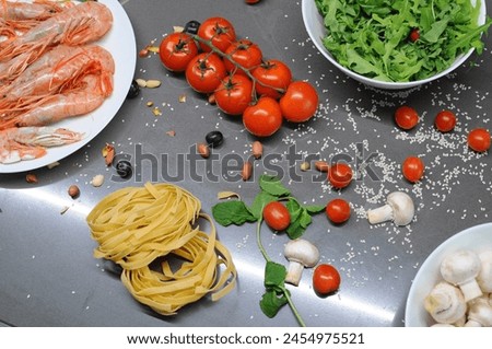 Spaghetti and fettuccine with ingredients for cooking pasta on wooden table with blank of round wooden kitchen board, top view. Rustic style. Flat lay. High quality photo