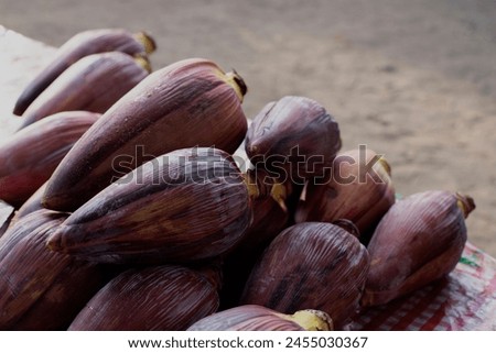 Banana flower pile on table. Tropical vegetable top view. Banana blossom salad ingredient. Philippine traditional cuisine spice. Banana bud fruit on market stall