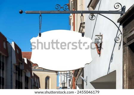 Blank Mockup Of Street Shop Vintage Signboard On Old Town Background. White Empty Retail Sign For Logo Or Banner