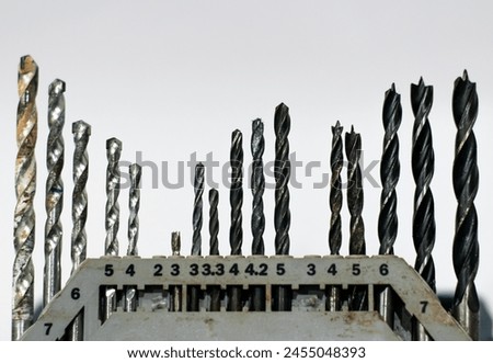 Photo of various sized and shaped steel drill bits set,white background with numbers showing sizes, in the studio photography style, macro shot from the side, with soft lighting, high resolution.
