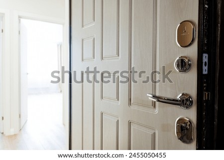 A wooden door with a sleek chrome handle is a fixture in the building, welcoming guests into the hallway of a modern home Royalty-Free Stock Photo #2455050455
