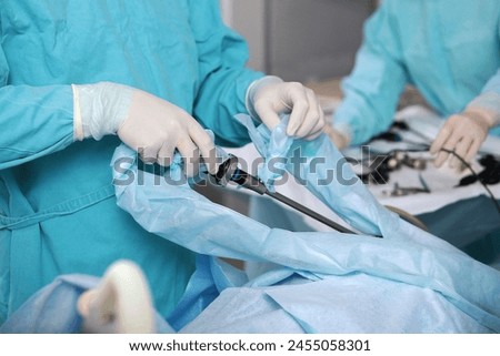 Laparoscopic instruments in hands of surgeon. Laparoscopic surgery. Surgery through small holes in abdominal cavity. Modern surgery. Royalty-Free Stock Photo #2455058301