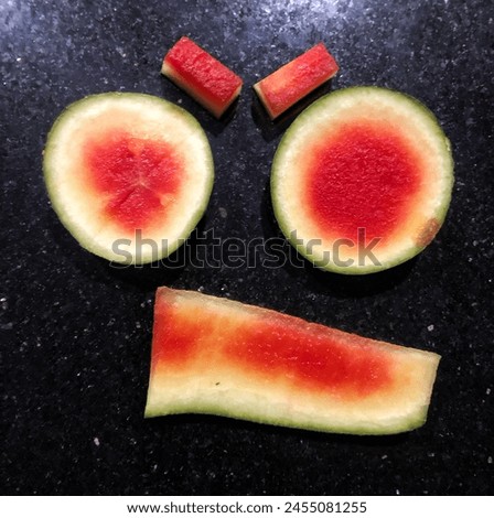Make an angry but cute monster face like in a cartoon from pieces of red watermelon rind
