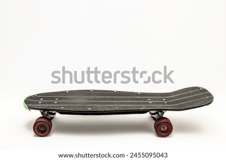 A skateboard with green wheels and a black deck. The skateboard is laying on its side