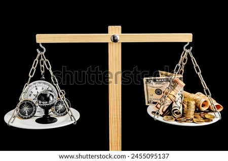 Two scales with one side holding a plate with a black ball and the other side holding a plate with a gold coin