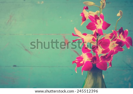 Purple orchid flowers in green vase with wooden wall, photo filter effect.