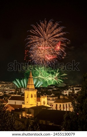 Nighttime fireworks at the Festa dos Tabuleiros in Tomar, Portugal, with the tower of the São João Baptista church in the spotlight.