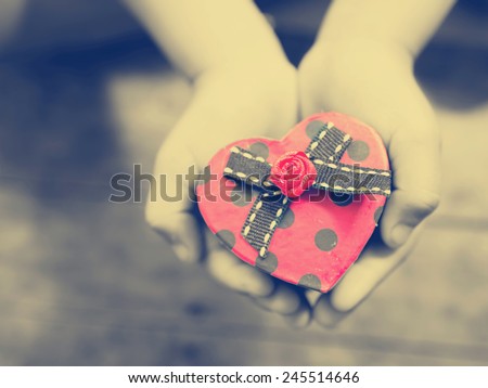 Red heart box in child's hands, photo filter effect.