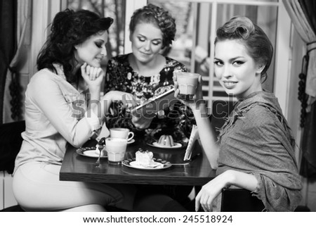 Three women friends in cafe looking at camera