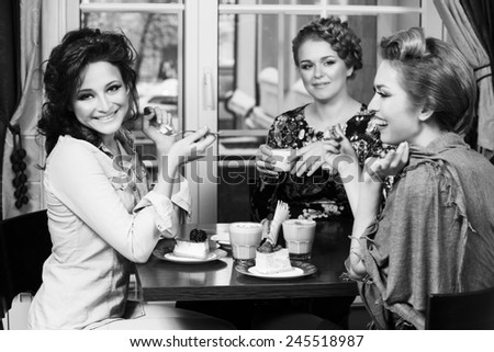 Three women friends in cafe looking at camera
