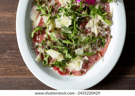 A top down view of a plate of steak carpaccio.