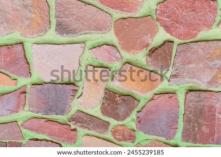 It is photo of colorful stones on green background. Its close up of the multicolored stone wall of building. It is photo of mosaic tile floor. It's view of wall texture.