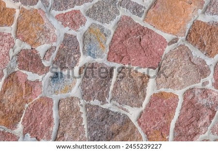 It's close up view of colorful wall. Its photo of multicolor stonewall. It is photo of the multicolored srone wall. its view of red sidewalk. It's view of mosaic stonewall