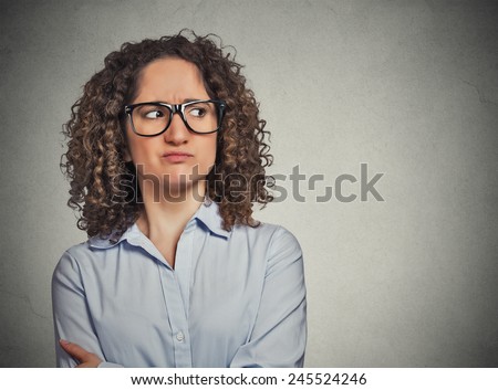 Displeased suspicious young woman with glasses looking sideways isolated on grey wall background. Negative face expression emotion perception  Royalty-Free Stock Photo #245524246