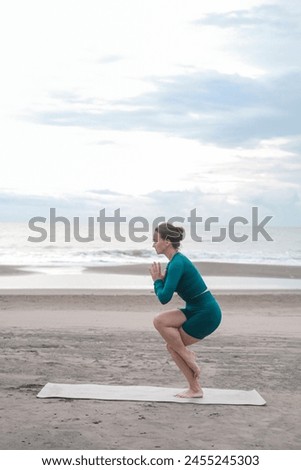 A young woman in sportswear on a black sand beach does a yoga asana. She is concentrated and calm. Stretching and meditation to the sound of the waves. Taking care of your body. Summer lifestyle.