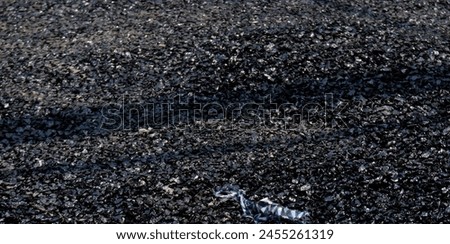 Stone chips melted on road due to high temperature in summer. Royalty-Free Stock Photo #2455261319