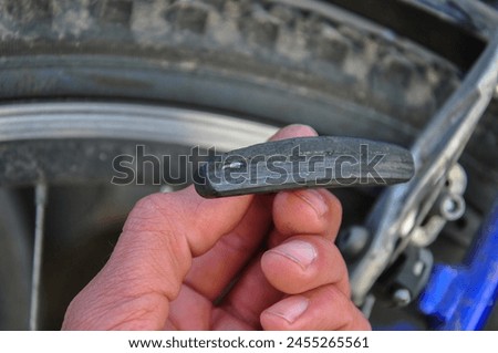 a worn bicycle brake pad in a hand in close-up. bicycle brake system repair. bike service. blurred background